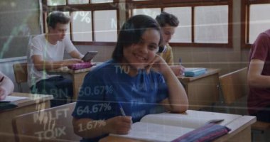 Finans çizelgeleri azalırken kameraya gülümserken sınıfta notlar yazan genç bir kız. Eğitim, öğrenme, teknoloji, finans, veri, takım çalışması, okul