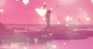 Animation of hearts over couple at beach. Holidays, free time and love concept digitally generated video.
