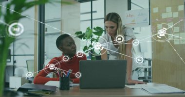 Resmi olarak iş birliği yapan meslektaşlar, ofislerinde dizüstü bilgisayarlarında dijital simgelerle birlikte belgeleri gözden geçirirler. İşbirliği, takım çalışması, modernlik, üretkenlik, yenilik, teknoloji, profesyonel