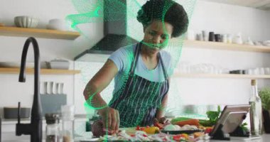 Ev aşçısı tablete bakıyor ve sebze doğruyor. Rehber gıda teknolojisi adımlarıyla örtüşüyor. Aşçılık, teknoloji, aşçılık, yerli, modern, tazelik, hazırlık