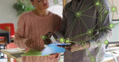 Meslektaşlar sayfaları çeviriyor ve finans tablolarının olduğu klasörlerin üzerinden ağ grafiği kaydırıyor. İşbirliği, takım çalışması, profesyonellik, veri analizi, ofis ortamı, iş stratejisi, dijital bağlantı