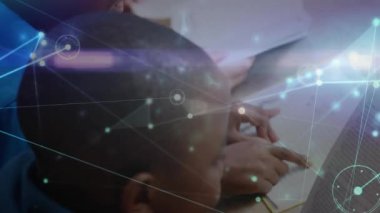 Çocuklar, masa başında kitabı açıp parmakla yazıları takip ederek ağ grafiklerinin altını çiziyorlar. Eğitim, işbirliği, yenilik, teknoloji, çocukluk, okur yazarlık, akıl hocalığı