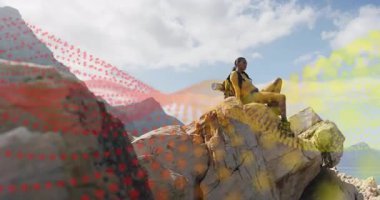 Kaya çıkıntısında oturan kadın, fitness yürüyüşüne devam etmeden önce kırmızı ve sarı parçacık dalgalarını tetikler. Macera, keşif, esneklik, açık hava, manzara, dinamik, sükunet