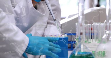 Laboratuvar önlüklü bir bilim adamı tüpler, formüller ve fotokopi alanındaki pipeti kullanarak sıvıyı transfer ediyor. Laboratuvar, araştırma, biyoteknoloji, bilim, analitik, kesinlik, yenilik