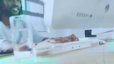 Ofis masasında su bardağıyla çalışan Afrikalı genç bir adamın dijital kompozit görüntüsü. İş, teknoloji, modern ofis, sağlıklı yaşam tarzı, çoklu pozlama.