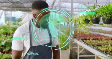 Bahçıvan seradaki tohumlara DNA arayüzü ile bakıyor ve bitki verilerini tarıyor. Bahçecilik, yenilik, botanikçi, sürdürülebilir, dahili, yüksek teknoloji, büyüme