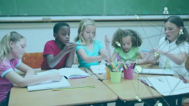 Elementary students opening notebooks grabbing colored pencils and coloring in classroom lesson. Classmates, education, art, creativity, collaboration, learning, childhood