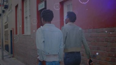 Animation of connections over back view of african american male friends walking on street. Network, connections, communication and technology concept digitally generated video.