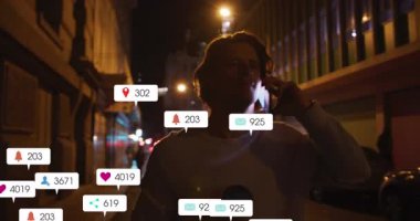 Animation of social media icons and numbers over caucasian man using smartphone. Social media and global communication interface technology concept digitally generated video.
