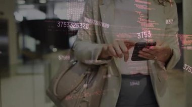 Caucasian businesswoman using smartphone in corridor of modern office.