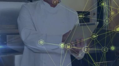 A chef is using a tablet in the kitchen and giving an ok sign, symbolizing communication and technology. This could represent data sharing and digital interfaces, as well as the network of connections that make them possible.