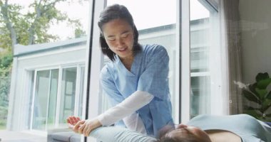 Physical therapist placing hands under patient arm on therapy table, lifting for improved mobility. Rehabilitation, physiotherapy, posture, mobility, healthcare, wellness, modern