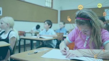 İlkokul öğrencisi kız not defteri yazıp masalarda beliren animasyon ticaret simgelerini aktifleştiriyor. Çocuklar, eğitim, öğrenim, sınıf, kırtasiye, dijital simgeler, ticaret