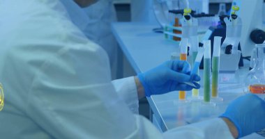 Mavi eldiven giyen teknisyen elleri laboratuvar tezgahında pipetlerle test tüpü rafı yerleştiriyor. Bilim, araştırma, yenilik, biyomedikal, laboratuvar, deney, profesyonellik