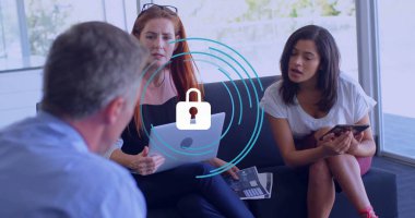 Ofis odasındaki koltukta oturan iş birliği yapan profesyoneller dizüstü bilgisayarlı akıllı telefon kullanıyorlar. İş, takım çalışması, modern, kurumsal, iletişim, gayri resmi, çalışma alanı