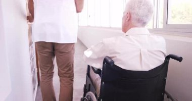 Hademe, yaşlı tekerlekli sandalyeyle tıbbi koridorun kapısını itip ahşap kapıya doğru yöneltiyor. Yardım, şefkat, sağlık, ulaşılabilirlik, sağlık, çevre, kıdemli