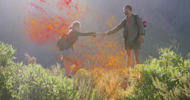 Yürüyüş partnerleri el ele tutuşuyorlar ve dağ macerasında kırmızı sarı tozun kıvrılmasına neden oluyorlar. Macera, takım çalışması, yoldaşlık, keşif, canlı, açık hava, arkadaşlık.