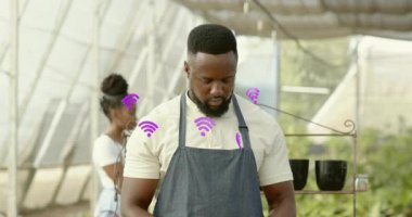 Erkek bahçıvan fideleri düzenliyor mor sinyal simgelerini etkinleştiriyor ve ağ halesi oluşturuyor. Botanik, takım çalışması, yenilik, sürdürülebilirlik, teknoloji, tarım, modern