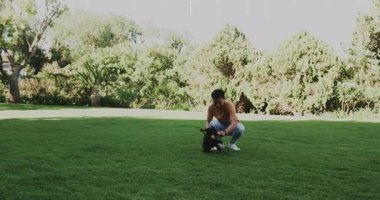 Bir adam lastik oyuncağı alıp arka bahçede el sallıyor ve evcil hayvan bakımı sırasında köpek kovalamaya neden oluyor. Köpek, açık hava, eğlence, arkadaşlık, yeşillik, gündelik