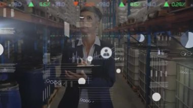 Orta yaşlı beyaz bir kadın depo müdürünün portresi stokları kontrol ediyor, bir depoda rafların yanında duruyor ve kameraya gülümsüyor. Sanayi ve sanayi işçileri kavramı.