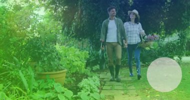 Animation of heart icon over caucasian couple in love holding hands in garden. Love and relationships concept digitally generated video.