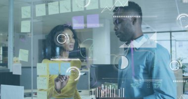 İş kıyafetleri giymiş iki iş arkadaşı ofislerindeki cam duvarlara yapışkan notlar düzenliyor. İşbirliği, beyin fırtınası, takım çalışması, iletişim, strateji, yenilik, üretkenlik