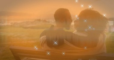 Gün batımında parlak bir örtüyle okyanusa bakan, hafif bir battaniyenin altında sarılan çift. Romantik, dinginlik, doğa, sükunet, alacakaranlık, arkadaşlık, açık hava