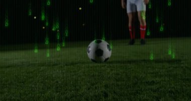 With green code streaming emerging, male athlete kicking soccer ball while displaying sports data. Athlete, sports, digital, motion, night, turf, competition