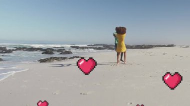 Sahilde dans eden mutlu Afro-Amerikan çiftlerin üzerinde yüzen kalplerin animasyonu. aşk, ilişki ve tatil konsepti dijital olarak oluşturulmuş video.