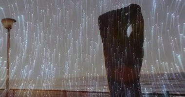 Erkek dansçı, AR teknolojisini gösteren ışık çizgileriyle deniz kenarında dans etmek için kollarını kaldırıyor. Siluet, performans, koreografi, okyanus manzarası, dijital alarm, ortam, minimalizm