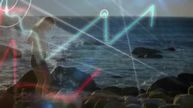 Kadın cebine uzanıyor ve akıllı telefondan verileri kontrol ediyor, kıyıda geziniyor, teknik çizelgeleri canlandırıyor. Macera, keşif, teknoloji, veri görselleştirme, açık hava, doğal, yenilik