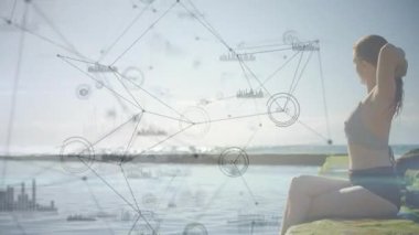 Güneşli kayalık sahilde saçlarını arkaya bağlayan ve teknoloji ağı grafikleriyle genişleyen bir kadın. Kadınsı, dinginlik, dijital, fütürizm, manzara, boş zaman, bağlantı