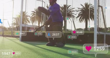 Hokey kalecisi kale kafesinde diz çöküp yükselen sosyal ikonlara tepki veriyor, şutu kurtarıyor ve filizleniyor. Sporcu, spor, aksiyon, açık hava, enerjik, canlı, yarışma