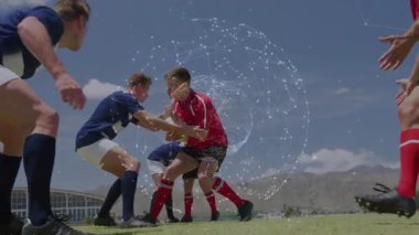 Kırmızı formalı top taşıyıcı, savunma oyuncularına hücum ediyor. Spor analizlerini gösteren küreyi çalıştırıyor. Atletizm, rekabet, takım çalışması, yoğunluk, spor stadyumu, dinamik, açık hava