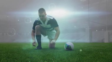 Rugby oyuncusu diz çökmüş, krampon bağlıyor, çizgiler kıvrılıyor, top kaldırıyor ve başlama vuruşu için koşuyor. Sporcu, spor, hareket, ekipman, rekabet, stadyum, dijital