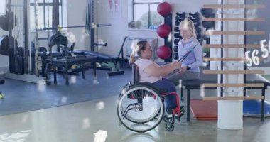 Antrenör bant takıyor ve verileri üst üste yerleştirirken tekerlekli sandalye kullanıcısını çalıştırıyor. Adaptasyon, güçlendirme, kapsayıcı, güç, rehabilitasyon, fitness, refah