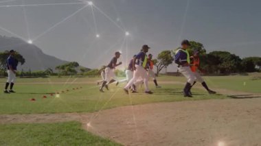 Koç, beyzbol hız talimi sırasında çimlerden koniye koşan oyuncuları selamlıyor. Sporcular, antrenmanlar, çeviklik, performans, spor giyim, açık hava, takım çalışması