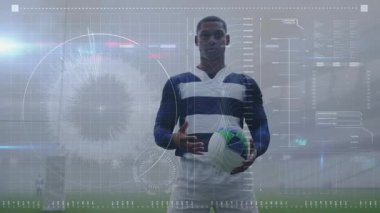 Holografik veriler spor analitiği için erkek sporcu futbol topunu kalça kısmına kaydırıyor. Sporcu, spor analitiği, fütüristik tasarım, dijital arayüz, stadyum, performans verileri, profesyonel spor
