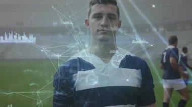 Rugby oyuncusu orta sahada duruyor ve takım arkadaşlarının ısındığı ölçümleri gösteren verileri etkinleştiriyor. Sporcu, performans, analitik, dijital, takım çalışması, stadyum, spor