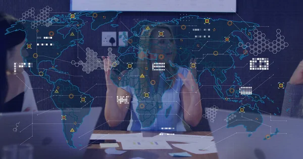 Önde gelen çizgili bluz giyen kadın toplantı odasında diz üstü bilgisayar kağıtlarıyla dijital harita kaplıyor. İş, işbirliği, strateji, teknoloji, takım çalışması, yenilik, sunum