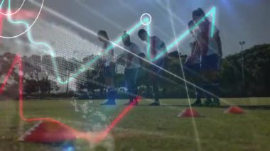 Dişi futbolcular, konilerin üzerinden atlayıp, ellerinde grafiklerle eğitim sürecini takip ediyorlar. Atletizm, fitness, takım çalışması, eğitim, performans, açık hava, modern