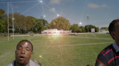 Rugby takım arkadaşları sahadan sahaya koşuyor kazak kaldırıyor ve canlı parlaklıklarla topu güvene alıyorlar. Takım çalışması, atletizm, rekabet, enerji, hareket, açık hava, dinamik