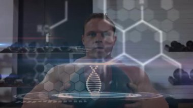 Erkek eğitmen tıp topu yerleştiriyor sonra da fitness teknolojisi için DNA sarmalını büyütüp etkinleştiriyor. Dijital, geleceksel, yenilik, biyomekanik, bilim, ilerleme, teknoloji