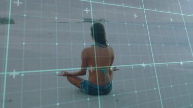 Kadının meditasyon duruşu şeffaf teknoloji şebekesinin kıyı şeridini haritalandırmasına neden oluyor. Dinginlik, farkındalık, teknoloji, açık hava, sükunet, manzara, uyum.