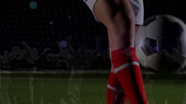 Forma 14 'teki oyuncu, selle aydınlanan futbol sahasında topa hafifçe vuruyor, yastık koyuyor, kalabalıkla kesişiyor. Sporcu, spor, antrenman, performans, açık hava, dinamik, yarışma