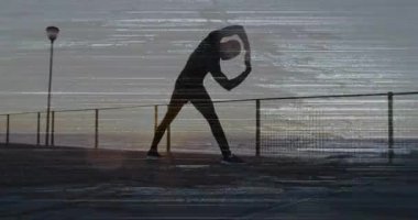 Egzersiz, gün doğumunda ısınmak için ufka bakarken iskelede esneme ve kıvrılma hareketleri yapıyor. Fitness, gündoğumu, sahil, siluet, canlılık, dayanıklılık, motivasyon