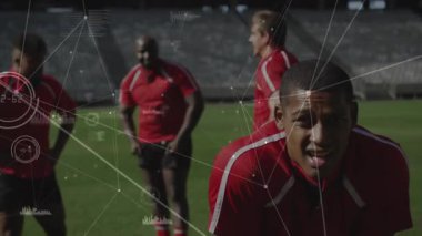 Öndeki sporcu spor grafiklerine eğilip, düzeltip, bağırarak tepki veriyor. Sporcular, performans, analiz, takım çalışması, stadyum, dayanıklılık, motivasyon