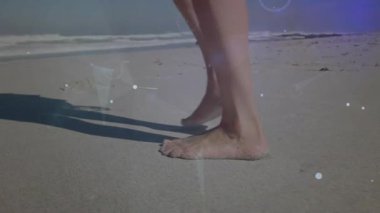 Sahilde çıplak ayakla yürüyen bir kadın sörfün yakınına ayak basıyor ve parçacıklarla teknolojik adımlar atıyor. Deniz kenarı, rahatlık, sükunet, minimalizm, dijital sanat, sükunet, sağIık