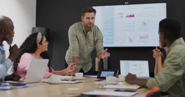 Modern ofisteki konferans masasına yaslanmış orta yaşlı bir adamı sunuyoruz. İş, takım çalışması, profesyonel, modern, strateji, işbirliği, analiz