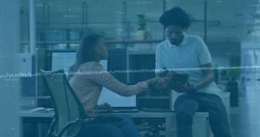 Modern açık-plan ofisindeki çift monitörlü tablet verileri üzerinden iş arkadaşına rehberlik eden bir kadın. İşbirliği, takım çalışması, teknoloji, modern, profesyonel, başlangıç, çalışma alanı